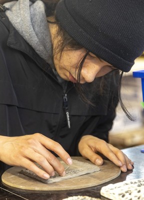 Thunder Churchill works on a clay tile that features the letter K, the first initial of Churchill's older brother who died of a drug overdose.  Churchill was taking part in a public workshop on Thursday, March 23, 2023.