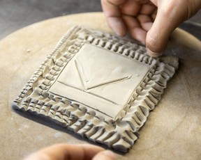 Thunder Churchill uses his fingernail to add detail to a clay tile that features the letter K, the first initial of Churchill's older brother, who died of a drug overdose.