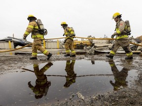 London Fire Department recruits haul a hose to the scene of a barn blaze that did an estimated $2 million in damage at the London Dairy Farms on Old Victoria Road one day prior. No animals or people were injured but several hot spots remained. Photo taken on Wednesday March 29, 2023. (Mike Hensen/The London Free Press)