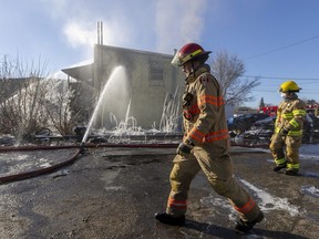 Two London firefighters walk near a warehouse at 820 Cabell St. that was hit by fire at about 1:30 a.m. on Thursday, March 30, 2023. (Mike Hensen/The London Free Press)