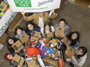 The Goodness Angels – Neva Yuksel, left, Selma Gokce, Leyla Cetintas, Melike Akin, Hira Canli, Ipek Özsoy, Berrak Cetintas and Muberra Tasan with Glen Pearson of the London food bank – help launch the food bank's spring food drive on Thursday, March 30, 2023. The group of young girls who came to Canada from different countries donated about 400 kilograms of food they had collected to the drive that runs until April 10. (Mike Hensen/The London Free Press)