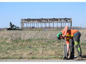 A construction worker dismounts a sign near a barn structure left from the demolition of a property on the future site of a Volkswagen battery plant in St. Thomas. (Calvi Leon/The London Free Press)