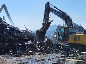 A backhoe operator digs into the smouldering rubble of a barn on Market Road north of Goderich that burned to the ground in a fire Thursday, April 14, 2023. (Huron OPP Twitter photo)