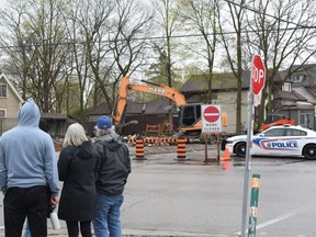 Onlookers watch as demolition crews remove the rubble from the Black Walnut cafe on Wortley Road on Monday, April 17, 2023, following a suspicious fire on Sunday. (Calvi Leon/The London Free Press)