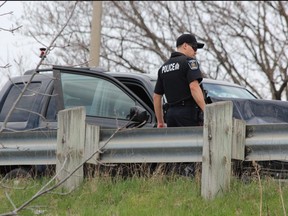 A London police officer inspects a vehicle involved in a four-vehicle crash near Highbury and Dundas Street that injured five people Saturday. Dale Carruthers / The London Free Press