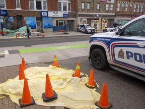 London police investigate a fire in Old East Village on Wednesday, April 5, 2023. Barricades surround a tarp outside the Ark Aid Street Mission at 696 Dundas St. whose facade shows fire damage. Police also were investigating a site across the street. (Mike Hensen/The London Free Press)