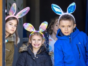 Athena Gilmour,7, Rhea Gilmour, 5, and Liam Duchnowski, 7, peer out from the castle doors at Storybook Gardens in London before being released into the park to hunt for Easter eggs on Friday April 7, 2023. (Mike Hensen/The London Free Press)