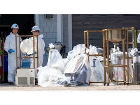 Working with police, a crew from waste management company GFL Environmental Inc. bags laboratory equipment at an alleged cannabis extraction lab in a high-end home on Commissioners Road. Photograph taken in London on Monday April 10, 2023. (Mike Hensen/The London Free Press)