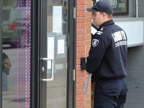 A London firefighter posts an inspection order on the door to a lower-level unit at 750 Richmond St. on Thursday, May 4, 2023. Police and city officials worked to shut down an alleged after-hours venue operating out of the commercial space as part of an investigation into a nearby double shooting on April 23. (Dale Carruthers/The London Free Press)