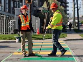 Sarnia city staffers Zach Price, left, and Paul Borody chuckle at a passerby’s comment while painting the crosswalk at London Road and Front Street North the colours of the London Knights on Tuesday May 9, 2023. The new paintjob was the follow-through to an OHL playoffs bet between Sarnia Mayor Mike Bradley and his London counterpart Josh Morgan. Terry Bridge/Sarnia Observer/Postmedia Network