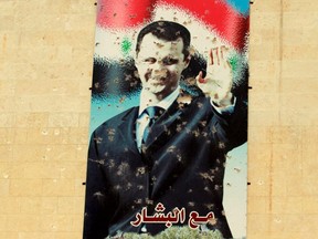 A damaged picture of Syrian president Bashar Al-Assad is seen on a wall in Idlib city, 2015. (REUTERS/Ammar Abdallah/File Photo)