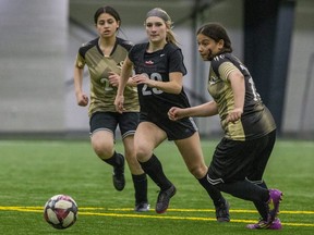 Halle Ledger of South collegiate institute  splits Westminster secondary school defenders Yasmeen Ahmed, left, and Batoul Aburas in a TVRA girls soccer game at BMO Centre in London on Tuesday May 2, 2023. (Derek Ruttan/The London Free Press)