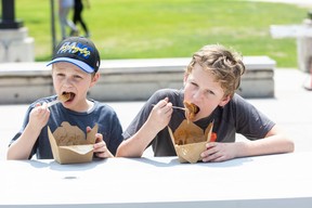 The Zhivov brothers, Leo, 9, (left) and Maks, 12, chow down during the final day of Poutine Feast at Victoria Park in London on Sunday.  “This is the best poutine I've ever had,” Maks said.