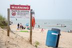 Several people take a dip in Lake Huron despite a warning sign posted at Grand Bend's south beach on Sunday July 16, 2023. (Derek Ruttan/The London Free Press)
