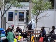 Refugees sit out side of 129 Peter Street in Toronto waiting for housing, some claiming six weeks on the street, Wednesday July 12, 2023.