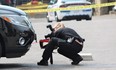 London police forensic investigator photographs a suspected bullet hole in an SUV