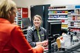 A cashier smiling at a customer who is buying groceries