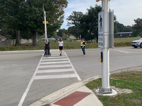 Colleen Perquin stops traffic to guide pedestrians across the crosswalk