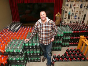 Shane Walton shows off some of the two litre bottles of pop he and his family will be giving out for Halloween at their Auburn Bay home in Calgary on Tuesday, October 31, 2023.