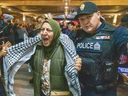 A pro-Palestinian protester is escorted by a London police officer out of a rally by Conservative Leader Pierre Poilievre at the Greek Canadian Community of London and Vicinity club in London on Thursday, Nov. 16, 2023. (Derek Ruttan/London Free Press)