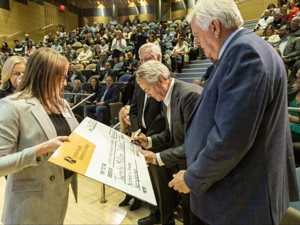 Three sons of the late  Archie Verspeeten, (left to right) Dennis, Mark and Brian, sign a giant cheque at Victoria Hospital during an announcement the family is donating $20 million to London Health Sciences Foundation on Tuesday, Nov. 28, 2023. (Derek Ruttan/The London Free Press)