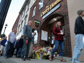 People stop to pay tribute outside of The Curry House restaurant in downtown Owen Sound during a walking vigil for owner Sharif Rahman on Sunday, Aug. 27, 2023. Rahman died a week after he was attacked outside his restaurant. (Greg Cowan/The Sun Times)