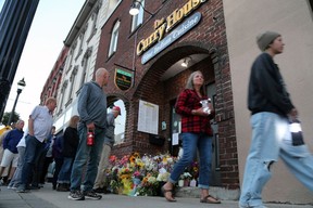 People stop to pay tribute outside of The Curry House restaurant in downtown Owen Sound during a walking vigil for owner Sharif Rahman on Sunday, Aug. 27, 2023. Rahman died a week after he was attacked outside his restaurant. (Greg Cowan/The Sun Times)