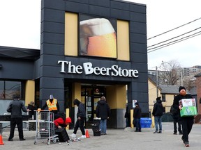 People line up in a parking lot for a long wait to return empties or buy beer at a Beer Store in downtown Toronto on Thursday, April 16, 2020. The Beer Store says it is expanding a delivery partnership with DoorDash Canada.