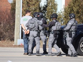 Sarnia Police with a man they placed in handcuffs Monday afternoon outside a duplex on Exmouth Street.