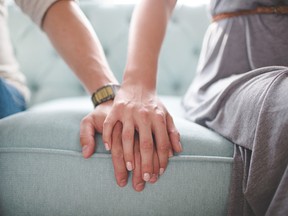 Waist photo of man and woman holding hands while sitting on a couch