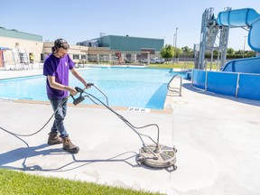Tyler Stevens cleans the deck of the swimming pool at Stronach