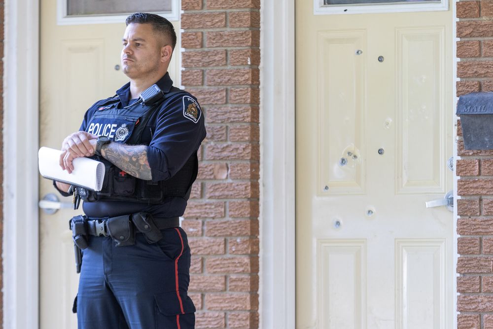 A London police officer guards the scene of a shooting on Boullee Street in London on Wednesday, Sept. 11, 2024. At least seven bullet holes are in the door behind him. (Derek Ruttan/The London Free Press)