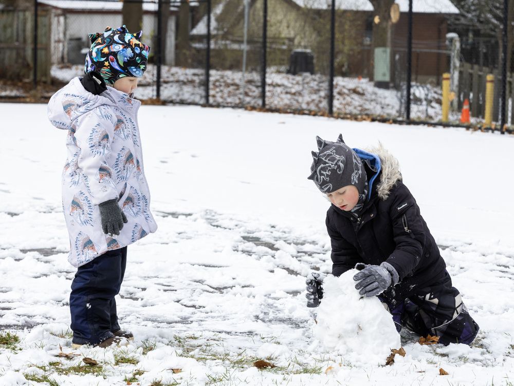 Three-year-old Lucas Norseyev watches his seven-year-old brother Thomas construct a small snowman at Jorgenson Park in west London on Monday December 2, 2024. (Derek Ruttan/The London Free Press)