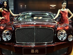 Models pose by a Bentley displayed at the Shanghai Auto Show in Shanghai (File Photo: PHILIPPE LOPEZ/AFP/Getty Images)