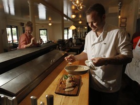 MONTREAL, QUEBEC: JULY 23, 2010 -- Nick Hodge puts the finishing touches on a chicken-fried steak meal at Restaurant Kitchenette in Montreal Friday, July 23, 2010. At the bar is caterer and maker of raw desserts Janis Dean. (John Kenney/THE GAZETTE)