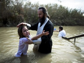 QASR AL YAHUD, WEST BANK - JANUARY 19:  (ISRAEL OUT) An Orthodox Christian child is baptized during Epiphany celebrations in the Jordan River January 19, 2012 at the Qasir al-Yahud baptismal site near Jericho, in the West Bank. Thousands of pilgrims gathered for the annual celebration at the site that the Eastern churches believes Jesus was baptised by John.  (Photo by Uriel Sinai/Getty Images)