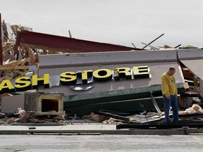 HARRISBURG, IL - FEBRUARY 29:  John Bonenberger looks at debris after a tornado damaged a strip mall where his bussiness was located February, 29, 2012  in Harrisburg, Illinois. According to reports, at least nine people have died in tornadoes in the Midwest. (Photo by Whitney Curtis/Getty Images)