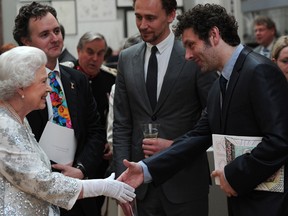 Britain's Queen Elizabeth II meets actor Michael Sheen as she visits the Royal Academy of Arts in central London on May 23, 2012.   (The very tall man in the middle is actor Tom Hiddleston, but no one told the  photographer, evidently. Since he is so tall, I guess  it was not possible to get the top of his head and the queen's hand into the same horizontal photo.  Michael Sheen and Tom Hiddleston worked together in Woody Allen's movie Midnight in Paris. Hiddleston went to Eton with the queen's grandson Prince William. Hiddleston plays the evil, yet very popular, Loki in the movie The Avengers, which is in cinemas now.)   (CARL COURT/AFP/GettyImages)