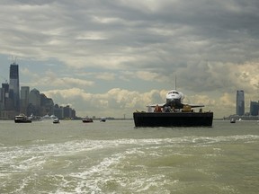 The US space shuttle Enterprise is towed by barge up the Hudson River with the New York skyline seen on the left and the Jersey City skyline on the right while on it's way to the Intrepid Sea, Air and Space Museum where it will be permanently displayed, Wednesday, June 6, 2012.      AFP PHOTO / NASA / Bill INGALLS