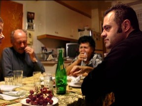 Filmmaker Tony Asimakopoulos (right) looks at Natalie Karneef.  Aristomenis Asimakopoulos (left) and Vassiliki Asimakopoulos, Tony' parents, sit behind them in this  still from the film Fortunate So.  (Courtesy of EyeSteelFilm)