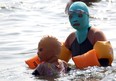 This picture taken on August 16, 2012 shows Chinese beachgoers wearing body suits and protective head masks, dubbed "face-kinis" by Chinese netizens, on a crowded public beach in Qingdao, northeast China's Shandong province. The face masks were initially designed to protect from sunburn but it turns out they are also quite handy at repelling insects and jellyfish, as many people in China dislike getting a tan, especially on the face.  AFP/GettyImages