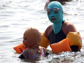 This picture taken on August 16, 2012 shows Chinese beachgoers wearing body suits and protective head masks, dubbed "face-kinis" by Chinese netizens, on a crowded public beach in Qingdao, northeast China's Shandong province. The face masks were initially designed to protect from sunburn but it turns out they are also quite handy at repelling insects and jellyfish, as many people in China dislike getting a tan, especially on the face.  AFP/GettyImages