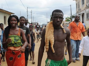 Ivorian people stare at a boy carrying around his neck a dead cat, he stole to eat, in the neighborhood of Abobo in Abidjan on September 27, 2012. The residents blamed the boy for stealing the cat and killing it to eat it. SIA KAMBOU/AFP/GettyImages