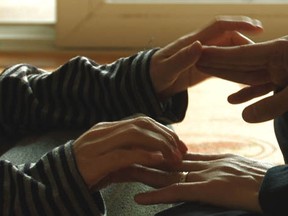 Soon-ho, left, communicates with her husband, Young-chan, by tapping on his fingers, in this scene from the documentary film Planet of Snail.