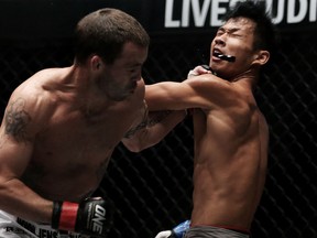 SINGAPORE - OCTOBER 06:  Jens Pulver of the USA connects with a left hand punch dislodging the mouth guard of  Zhao Ya Fei of China during the One Fighting Championship, Bantamweight Grand Prix bout at Singapore Indoor Stadium on October 6, 2012 in Singapore.  (Photo by Chris McGrath/Getty Images)