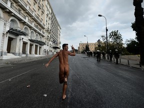 A naked demonstrator flashes the victory sign while running in Athens during a demonstration against the vist of the German Chancellor Angela Merkel on October 9, 2012.   Athens went into security lockdown for a landmark visit by German Chancellor Angela Merkel, an austerity hate figure in Greece whose arrival will be greeted by union and opposition party protests. Thousands of police fanned out across the capital, creating a large safety zone for Merkel's meetings with Prime Minister Antonis Samaras and President Carolos Papoulias in which all gatherings and protests have been banned. ARIS MESSINIS/AFP/GettyImages