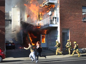 Pedestrians run from the scene as firefighters enter a burning triplex. A major fire started early in the afternoon behind the triplex at the corner of Bellechasse and St-Denis in Montreal's Plateau district on October 18, 2012 . No injuries were reported and a pet turtle was among the occupants rescued. (Marie-France Coallier / THE GAZETTE)