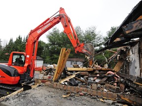 A backhoe sifts through the debris of Allen Bassenden's home in St-Lazare