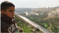 Gibreel, son of filmmaker Emad Burnat, looks at the new housing that's been built since he was born.