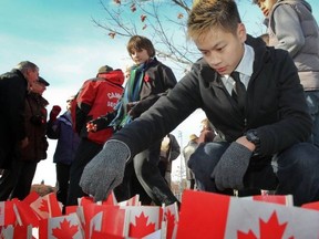 Macdonald High student Justin Vong-Le plants his Canadian flag into the ground around the monument to Macdonald HS and Macdonald College alumni who died during World War II.
